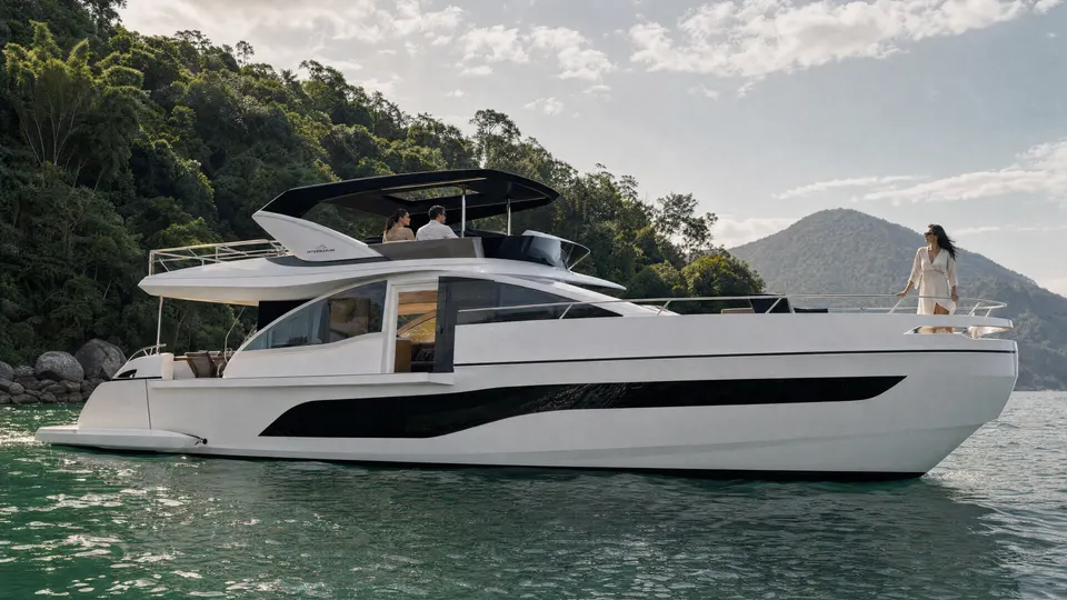 A Intermarine 25M inteira, de perfil, fundeada em Angra, com uma mulher em pé na proa